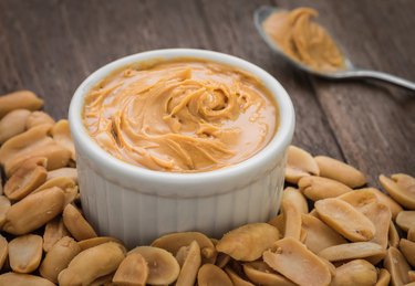 Peanut butter in bowl and peanuts