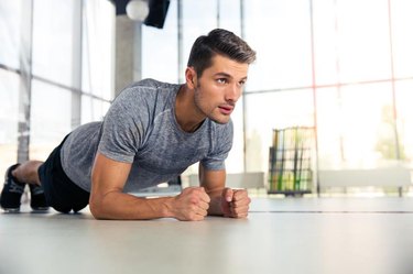 Portrait of a fitness man doing planking exercise in gym