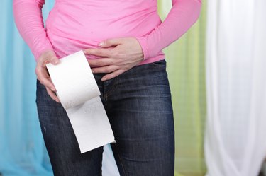 Woman with tummy ache and toilet paper
