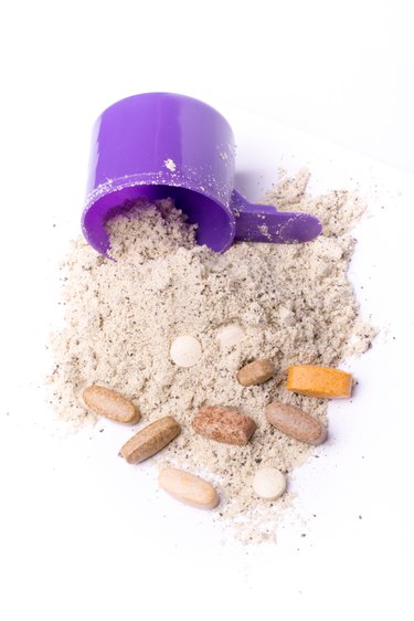 Whey protein powder in scoop with vitamins and plastic shaker