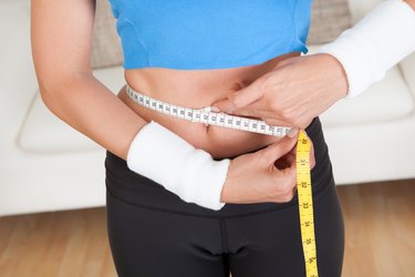 Happy woman measuring her waist