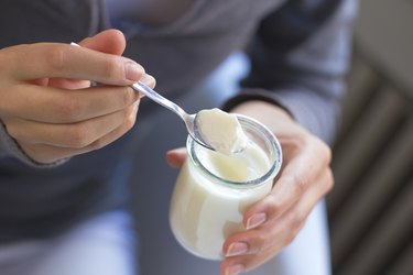 young beautiful woman eating yogurt at home