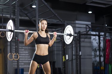 Young woman lifting barbell at gym