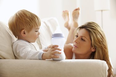 young mother feeding her son on the sofa at home