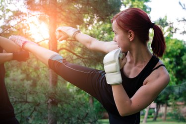 Young woman boxer workout on outdoors on sunny summer day.