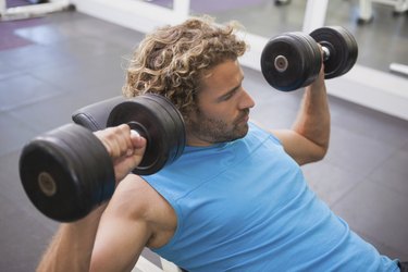 Side view of man exercising with dumbbells in gym