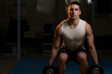 Young Men Doing Squats With Dumbbell In Gym