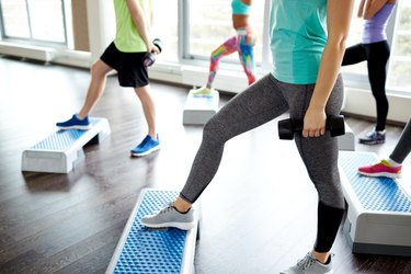 group of people with dumbbells and steppers