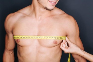 Woman's hand measuring man's chest with a yellow tape