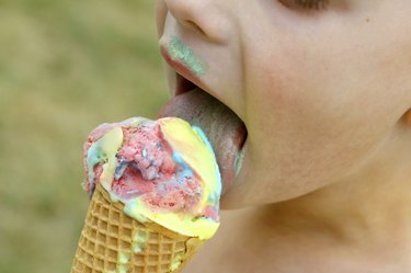 Close Crop of Child Eating Rainbow Ice Cream Cone