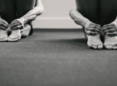 Nice image of two people in identical rabbit pose. This was shot from behind with natural light coming through a window, and has some copy space below the feet.