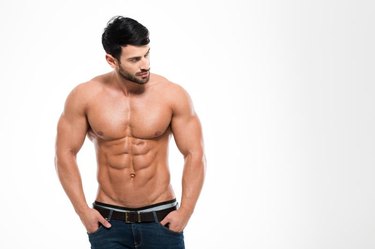 Portrait of a fitness man with nude torso standing isolated on a white background