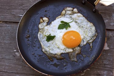 A sunny side up egg on a dark, round plate