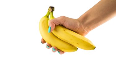 Two yellow banana in a female hand with a manicure