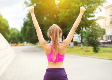 Fitness happy runner woman enjoying after training in city park,
