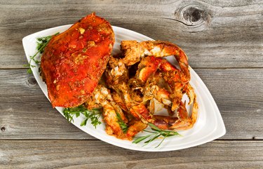 Spicy cooked crab on white plate with rustic wood