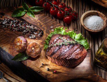 Beef steaks with spices on a wooden tray.