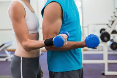 Fit couple exercising with blue dumbbells