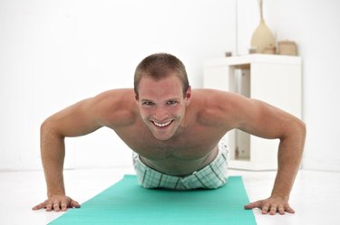 young man doing pushups on a green mat