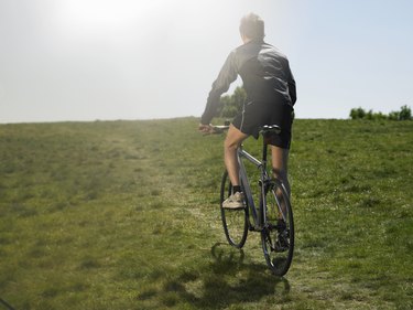 Mid adult man riding bicycle uphill, rear view