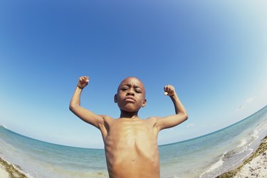 Low angle view of a boy flexing his muscles on the beach