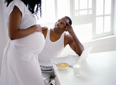 side profile of a pregnant woman standing and talking to her husband