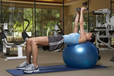 Woman exercising with dumbbells on fitness ball