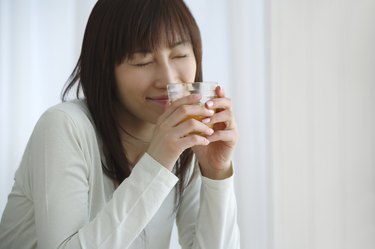 Young Woman Holding a Glass of Orange Juice, Side View