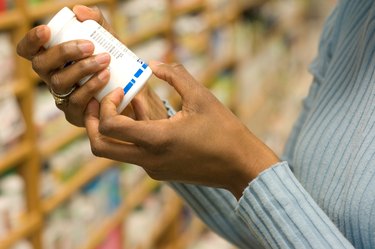 Hands on a vitamin bottle, reading label on bottle