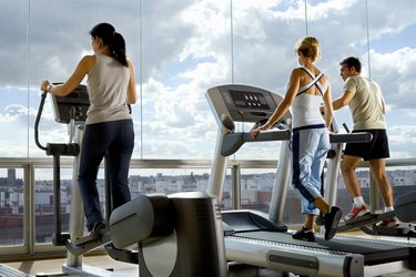 People using exercise equipment in front of a window