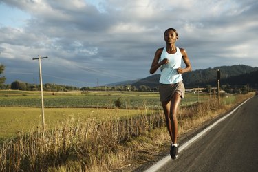 Young woman jogging by road in rural landscape