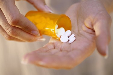 Close-up of a person's hand holding a bottle of pills