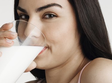 Young woman drinking milk, smiling, portrait, close-up