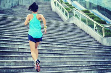 young sports woman running up stone stairs