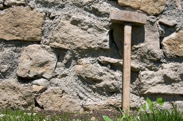 Sledge hammer leaning against stone masonry wall