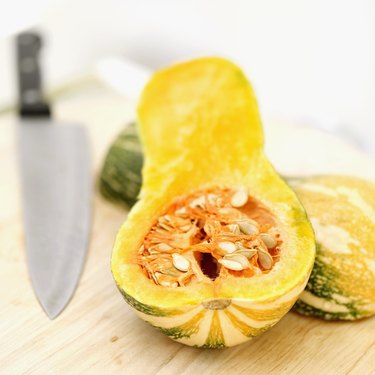 Close-up of a cut open pumpkin on a cutting board with a knife