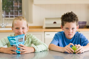 Girl and boy with crisps and apple