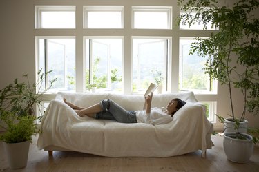 Woman reading book on sofa in living room