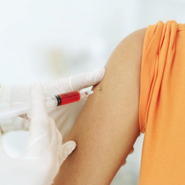 Close-up of a doctor's hands injecting the arm of A Woman