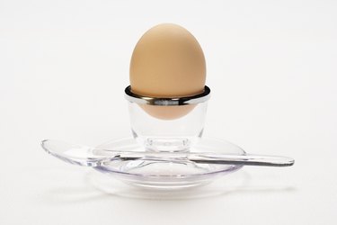 Hard boiled egg in glass cup with spoon