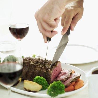 Close-up of the hands of a person cutting a meatloaf