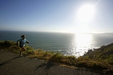 Woman jogging on road beside ocean,  California,  USA