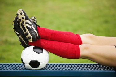 Soccer player resting feet on ball