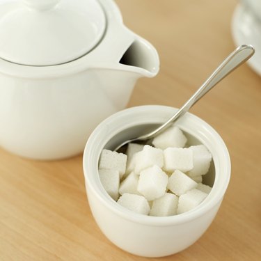 high angle view of a teapot and a bowl of sugar cubes with a spoon