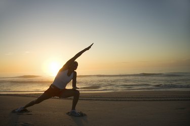 Woman stretching at beach at sunrise