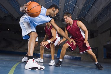 Man dribbling basketball against defenders