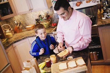 Father making peanut butter and jelly sandwich for son