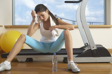 Woman sitting on treadmill after work out in gym