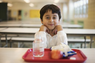Boy with lunch sitting in school cafeteria