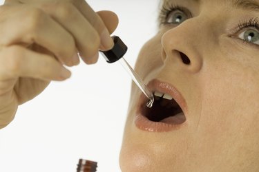 Woman taking oral medication with a dropper